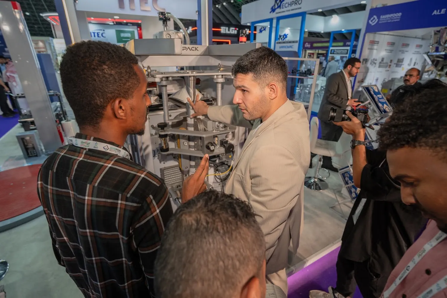 Visitors gathered around a machine while an ITEC engineer explains it, Saudi Food Manufacturing 2026