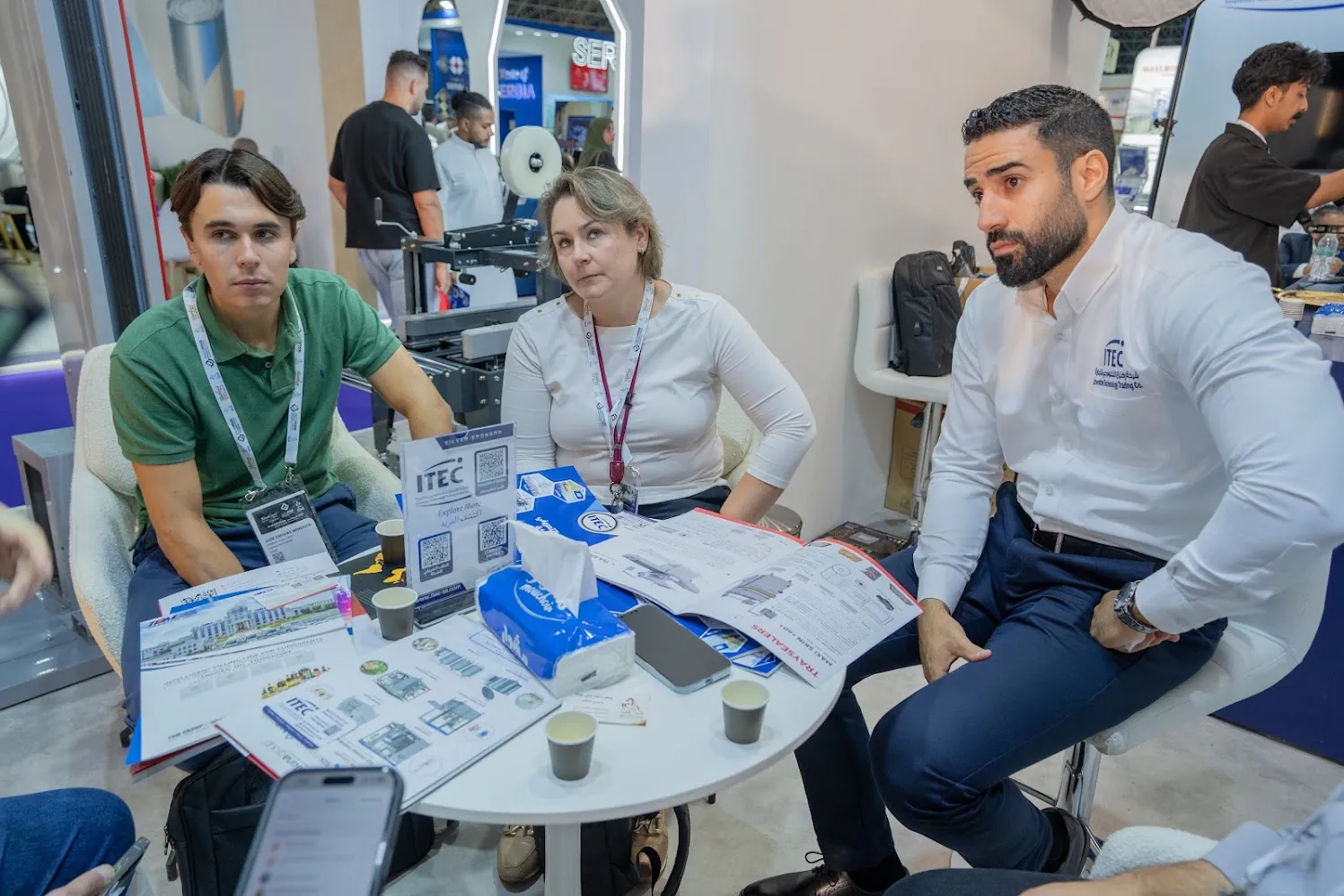 Three people at a table with brochures during a meeting on the ITEC stand, Saudi Food Manufacturing 2026